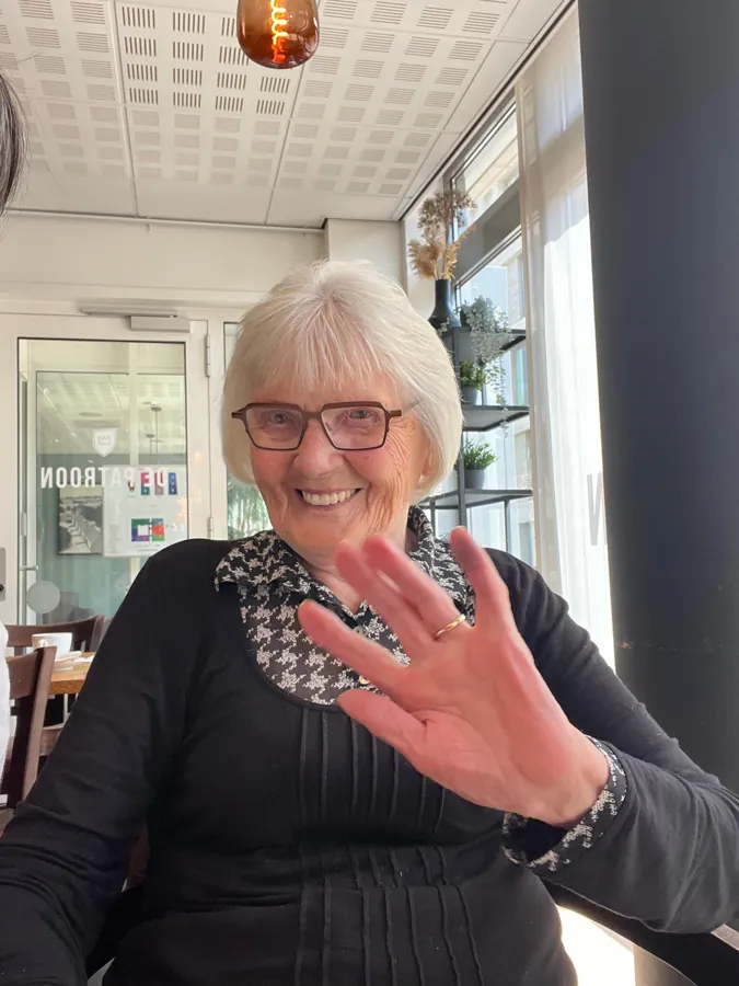 A smiling woman waves at the camera