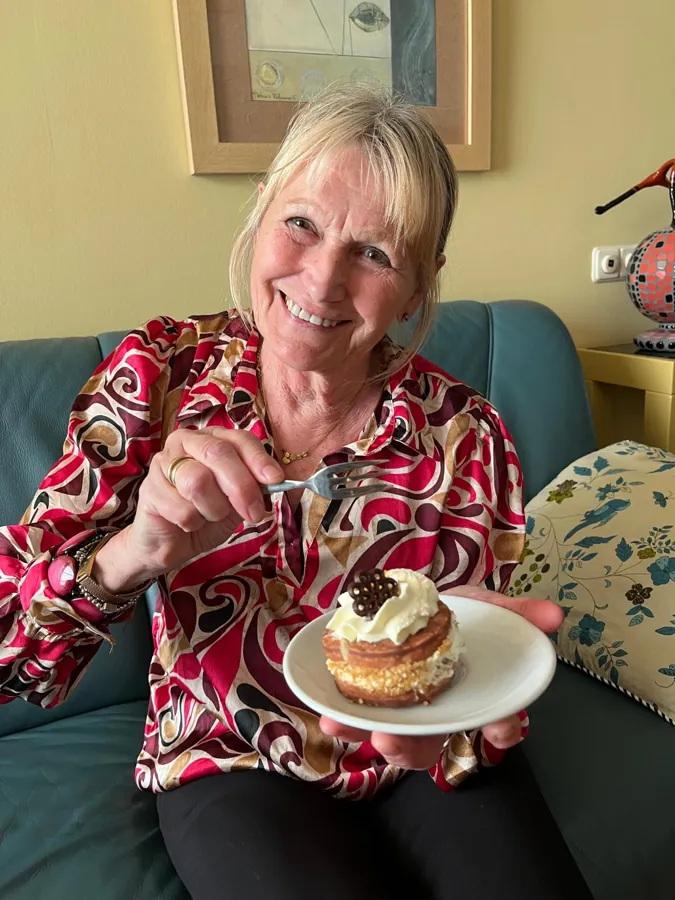 A smiling woman enjoys a piece of cake